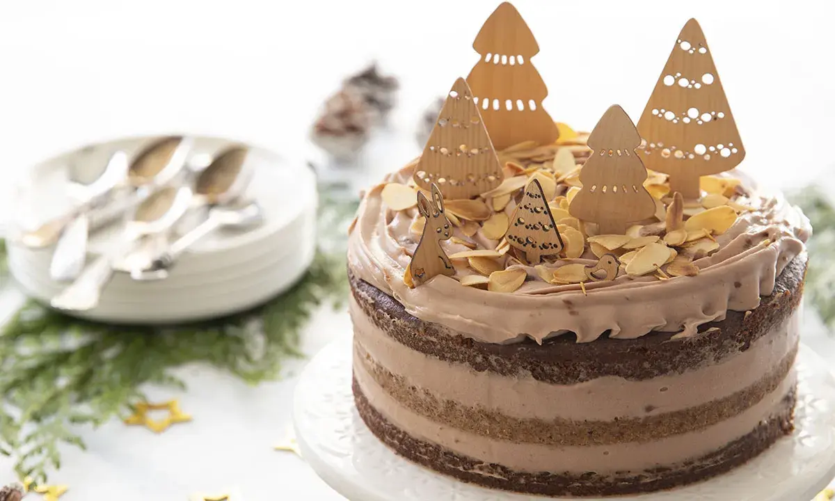 Gâteau au chocolat décoré d'arbres de Noël en bois, d'amandes effilées et d'un lapin.