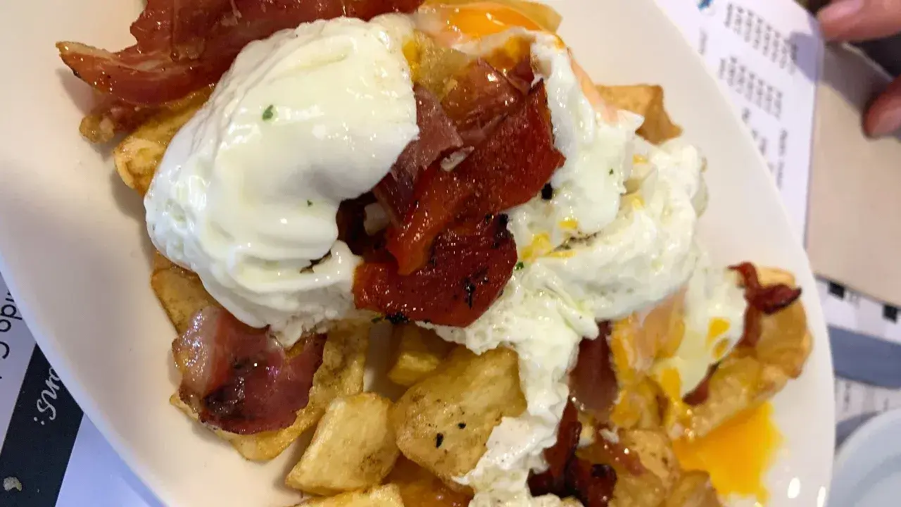 Un plato de patatas fritas con huevos escalfados y jamón, típico de los furanchos de Pontevedra.