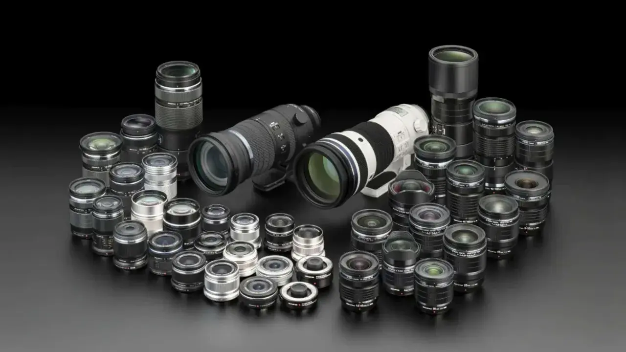 Collezione di obiettivi fotografici di varie dimensioni, dai teleobiettivi ai grandangolari, disposti su sfondo nero. Un vero tesoro per ogni appassionato di termini fotografici.