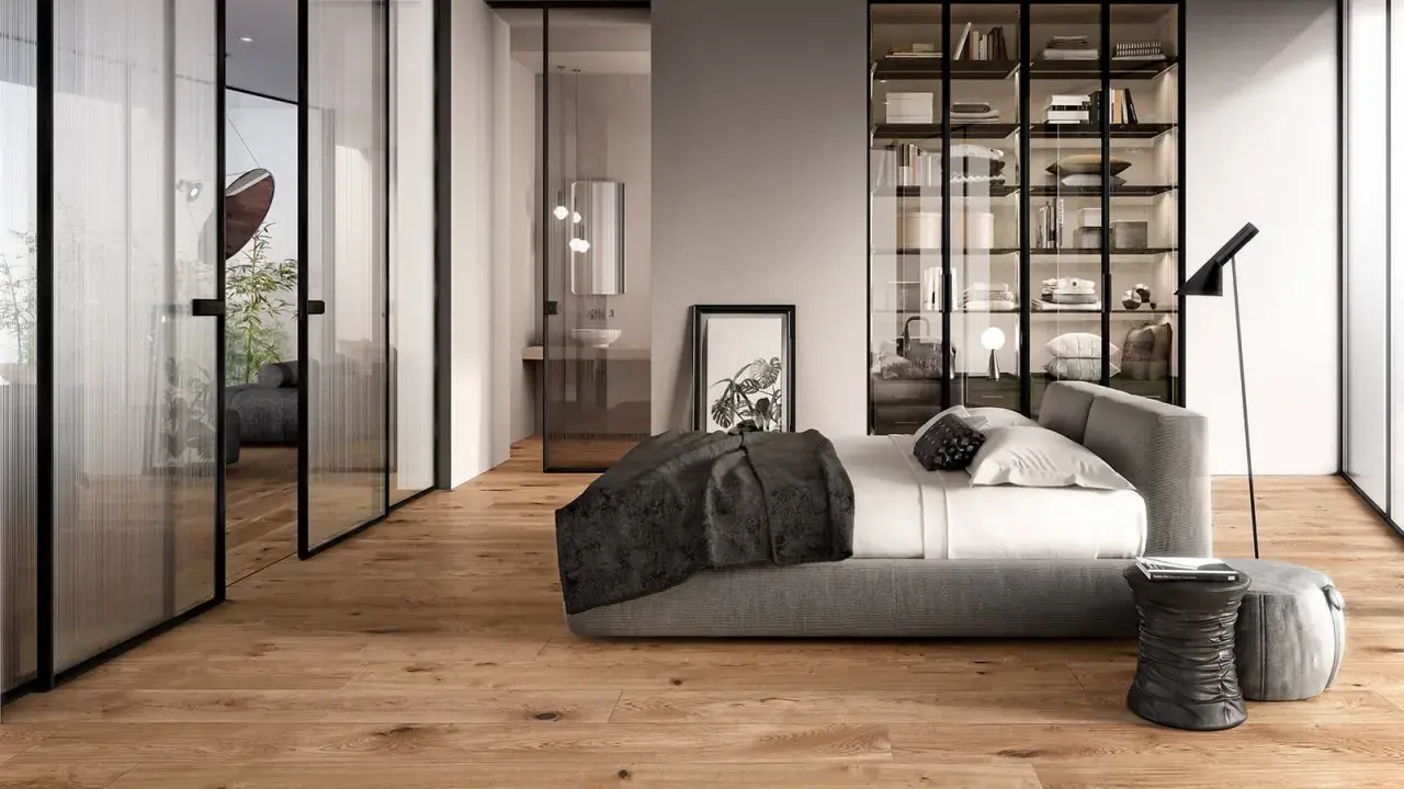 Modern bedroom with glass doors, a bed, and a wardrobe. The doors are designed to transform a hinged door into a sliding one, saving space.