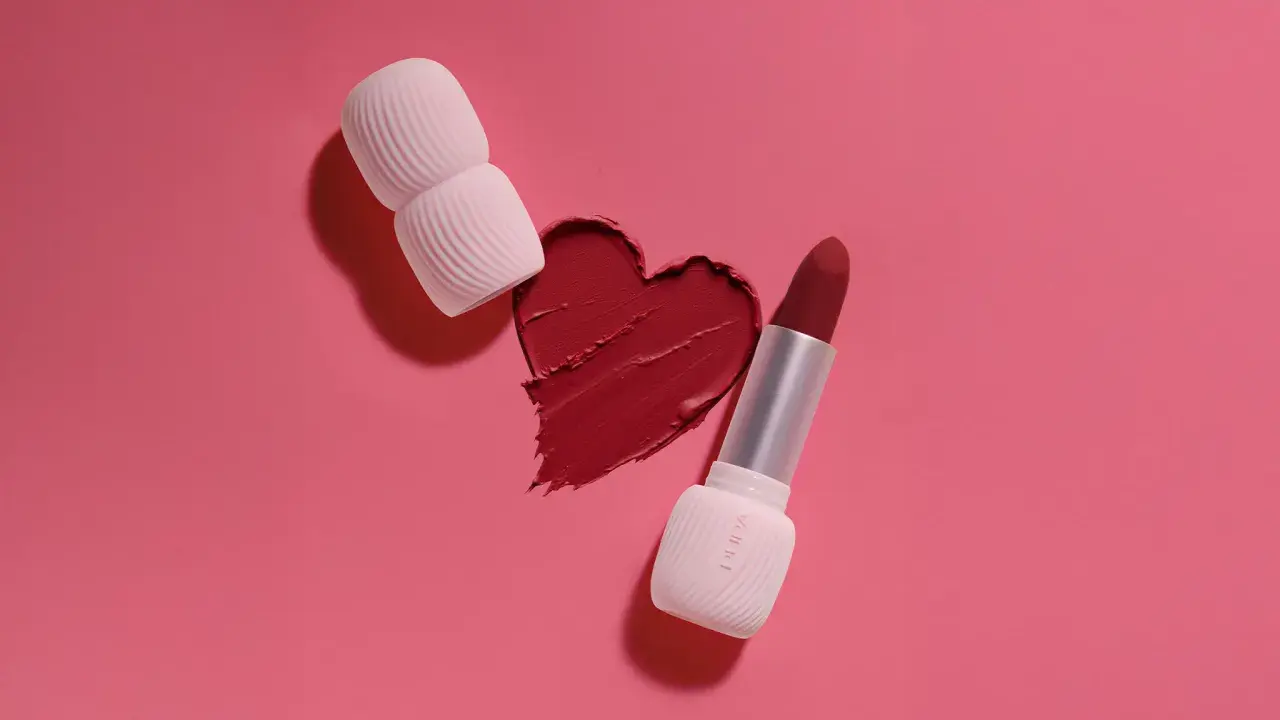 Un cuore di rossetto rosso, con un rossetto e un applicatore, mostra diversi tipi di rossetto.
