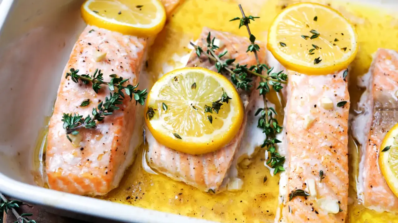 Saftiger Lachs mit Kartoffeln im Ofen, garniert mit Zitronenscheiben und frischem Thymian.