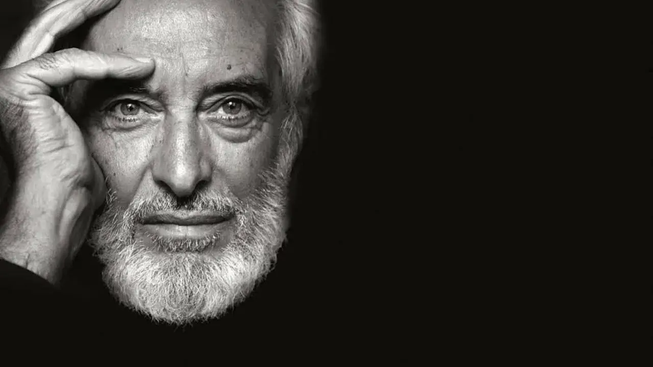 Ritratto in bianco e nero di un uomo anziano con barba bianca, mano sulla fronte. Un fotografo napoletano famoso cattura uno sguardo intenso.