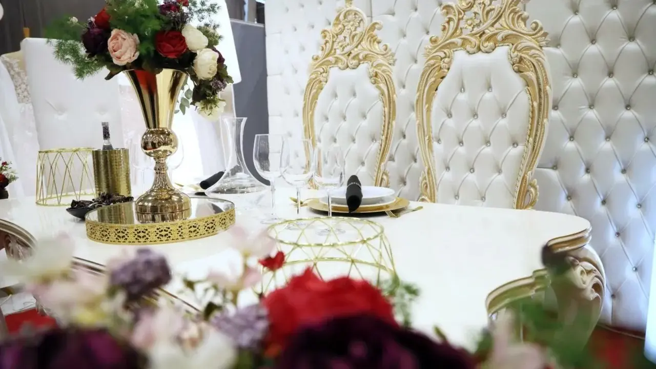 Elegancki stół z kwiatami i złotymi zdobieniami. Zastanawiasz się, ile się płaci za ślub cywilny w takim otoczeniu?