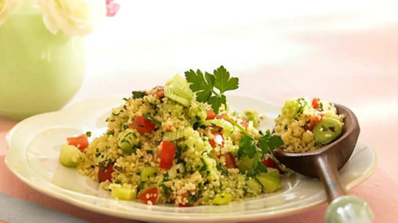 Frischer Couscous-Salat mit Tomaten, Gurken und Kräutern, garniert mit Petersilie. Ein Löffel voller Genuss.