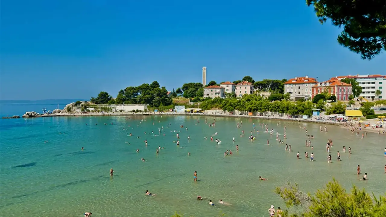 Una giornata di sole sulle spiagge Croazia, con gente che nuota e si rilassa nell'acqua cristallina.
