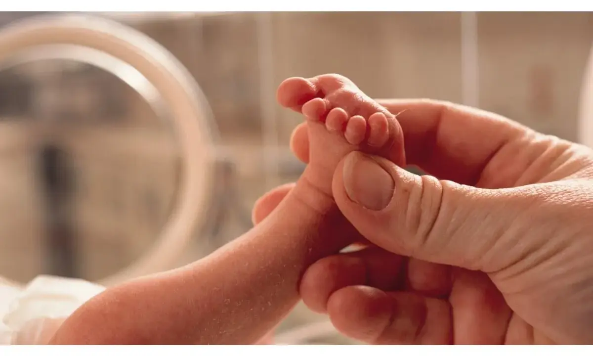 Un piedino di neonato tenuto da una mano adulta. Un'immagine che evoca la delicatezza e l'importanza della valutazione Apgar, un test per valutare le condizioni del neonato alla nascita.