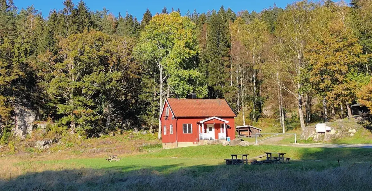 Rött hus i Svartedalen, perfekt för en vandring. Höstfärger i skogen och en solig äng.