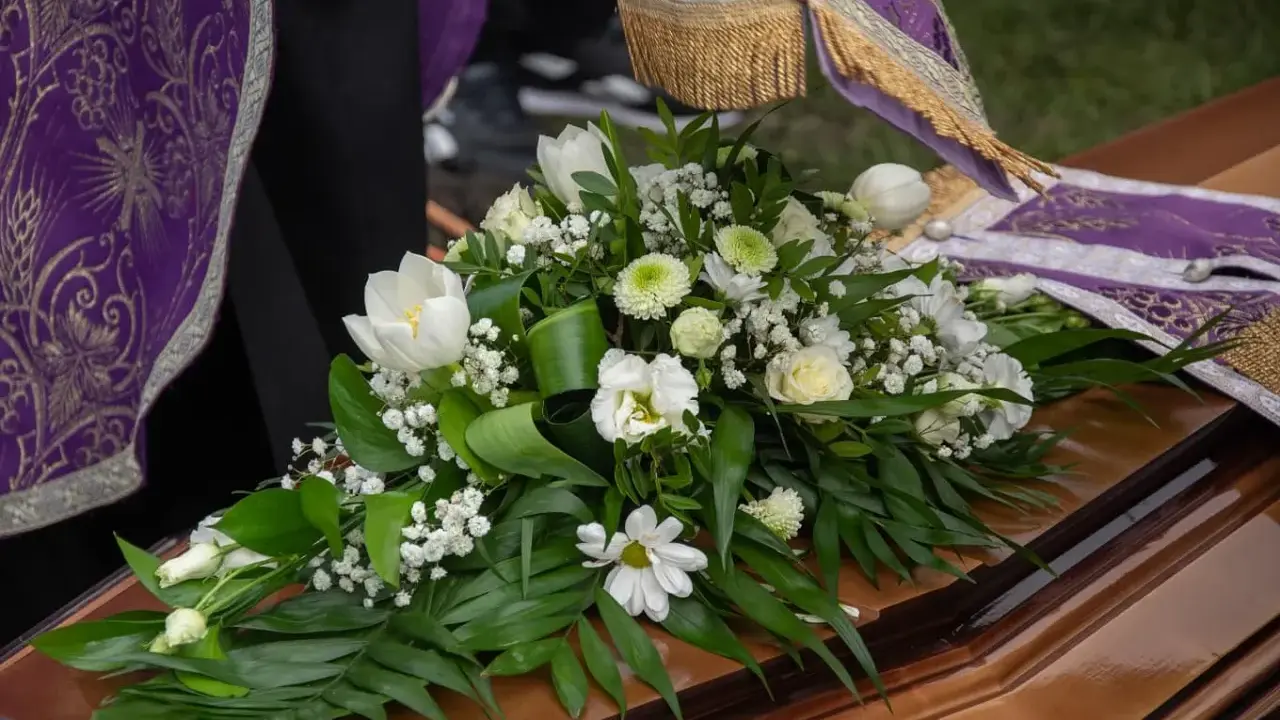 Białe lilie i inne kwiaty na trumnie, symbol pożegnania. Uroczysty bukiet na pogrzeb.