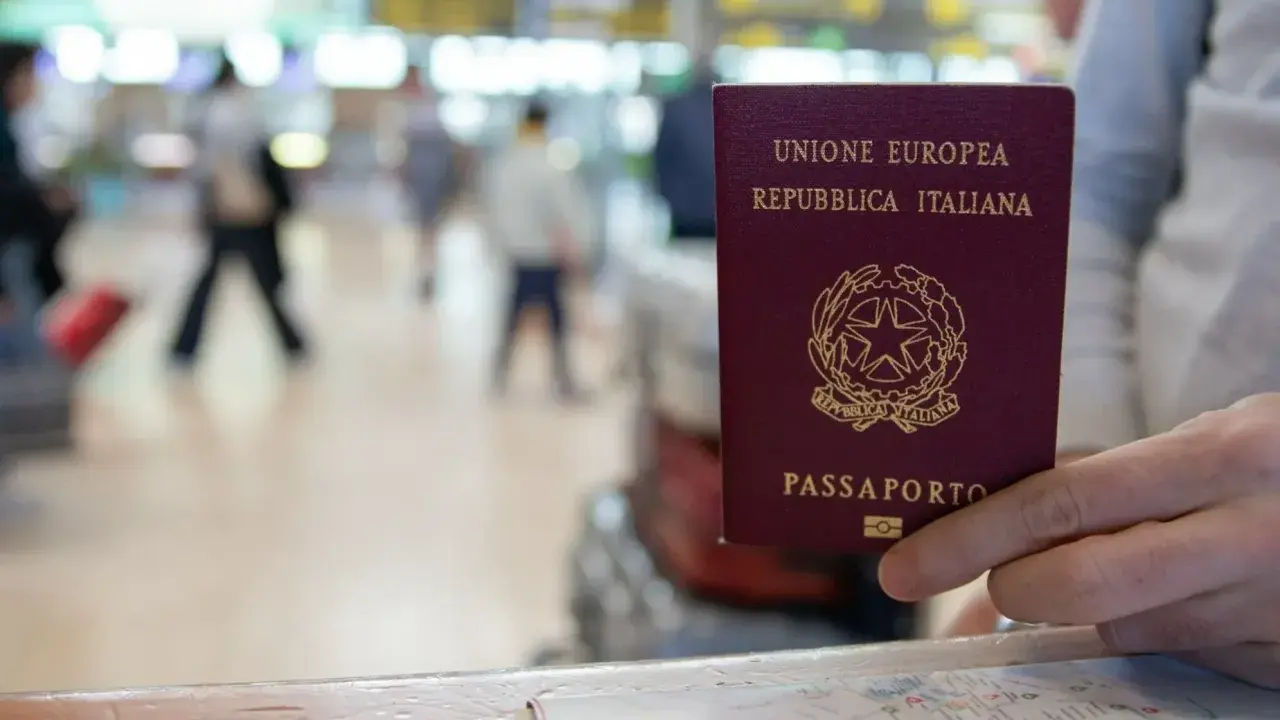 Włoski paszport w dłoni, gotowy do podróży po Europie. To idealny sposób na wakacje bez paszportu, gdy podróżujesz w strefie Schengen.
