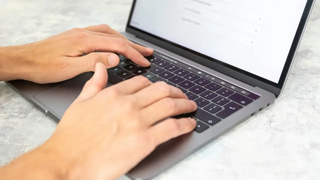 Dłonie piszą na laptopie. Może to być praca dla agencji copywriterskich, tworzenie treści lub analiza danych.