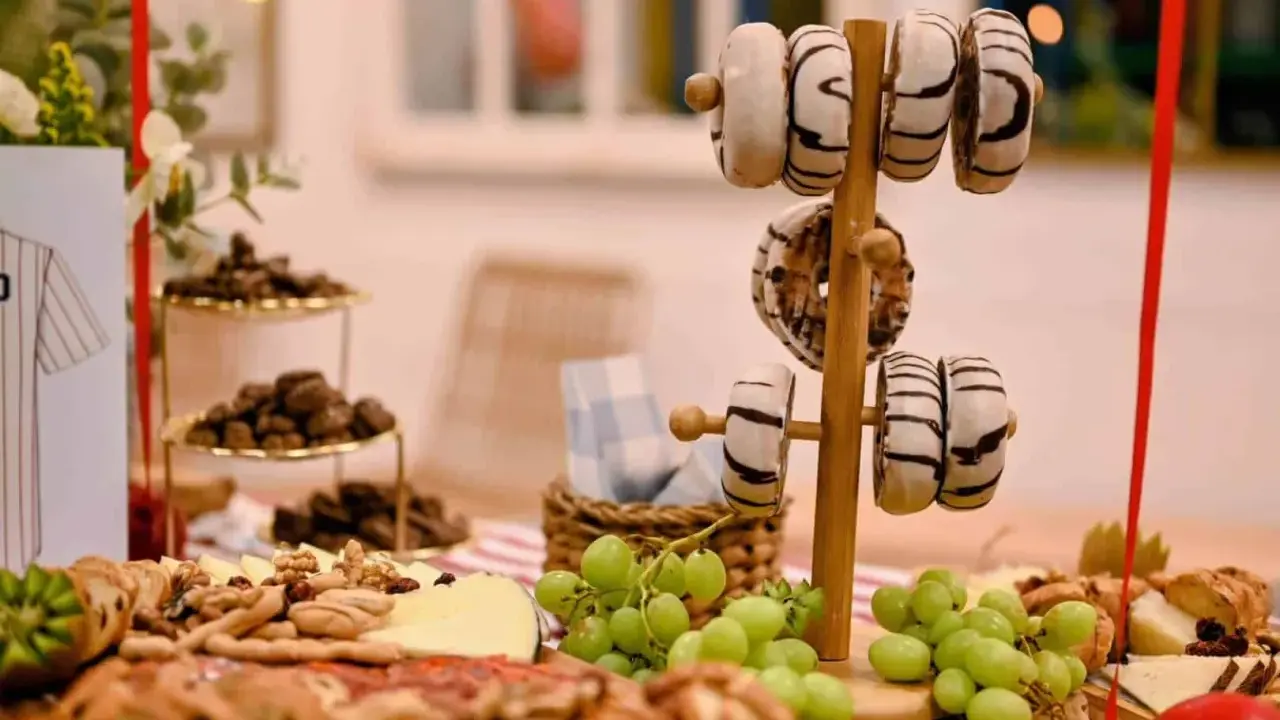Deliciosa merienda de cumpleaños para adultos: donuts, quesos, frutos secos y uvas.