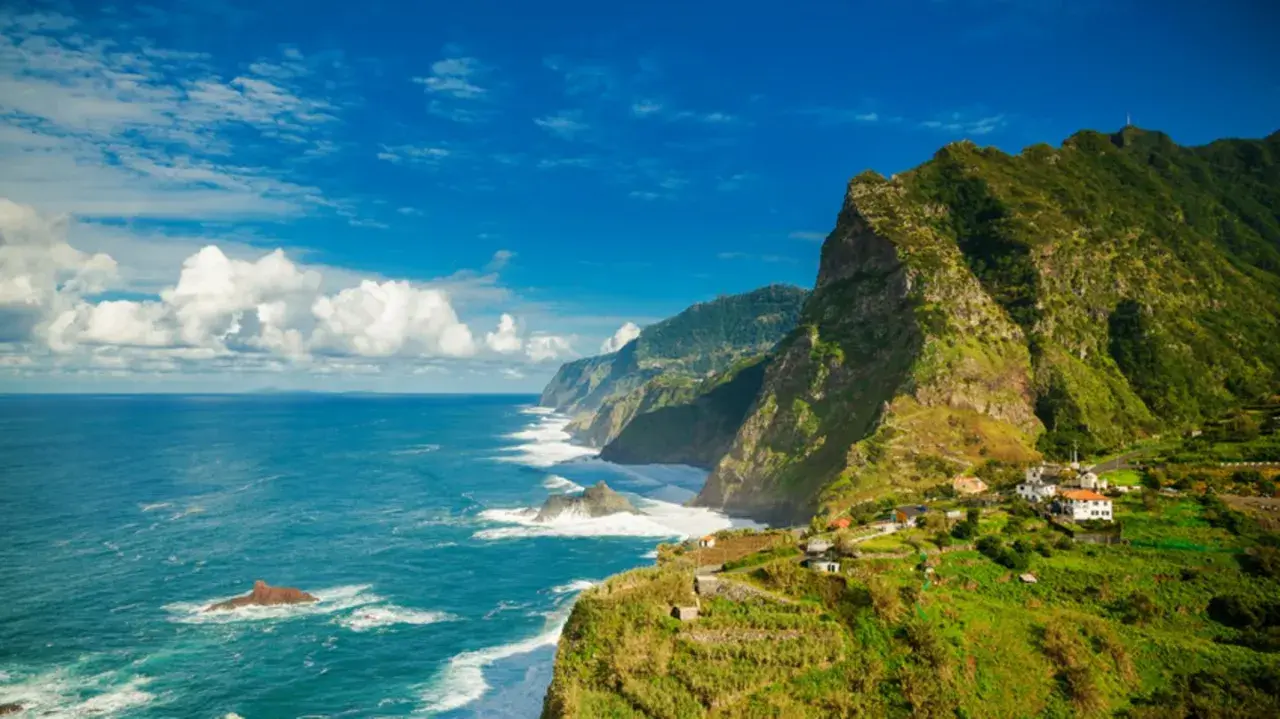 Grüne, steile Küsten mit kleinen Häusern, die sich an den Hang schmiegen. Das azurblaue Meer brandet an Felsen. Ja, Madeira in der EU bietet diese atemberaubende Aussicht.