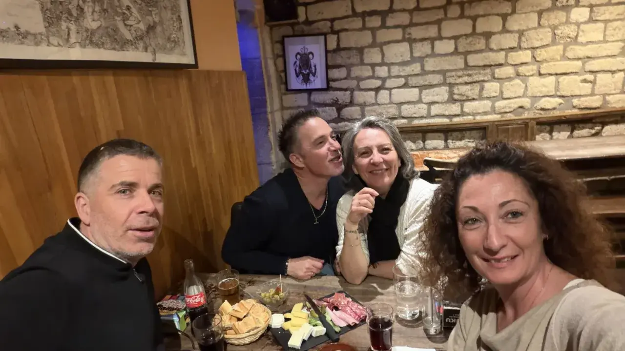 Ambiance chaleureuse dans la taverne médiévale Paris. Quatre amis partagent un repas convivial, entre rires et dégustations.