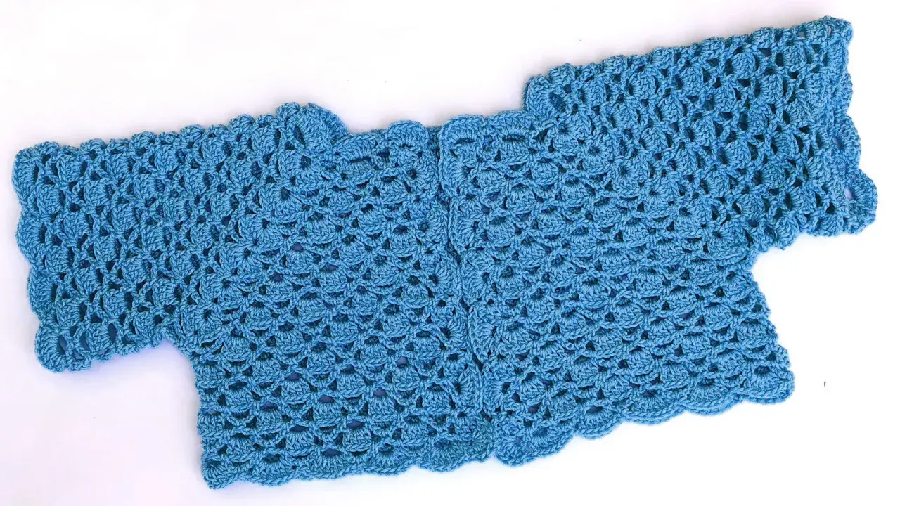 Bolero crochet azul con un delicado patrón de escamas y borde ondulado.