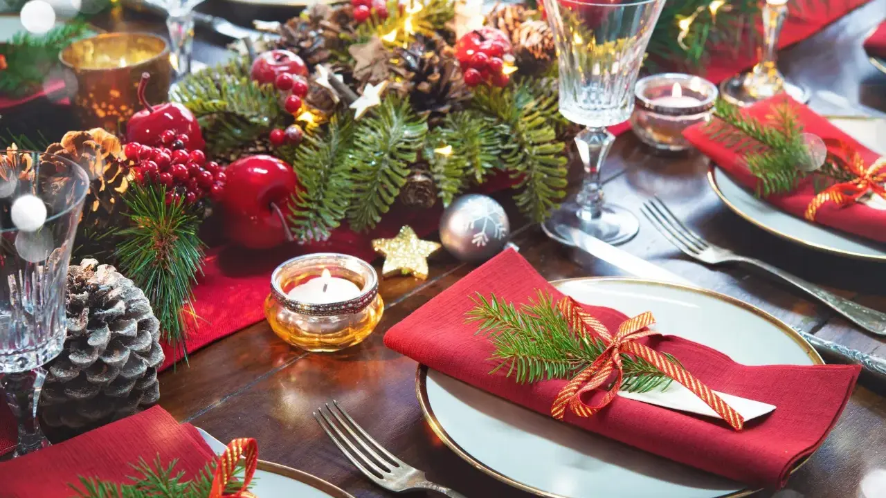 Vackert dukat på julbordet med röda servetter, granris och julgranskulor.