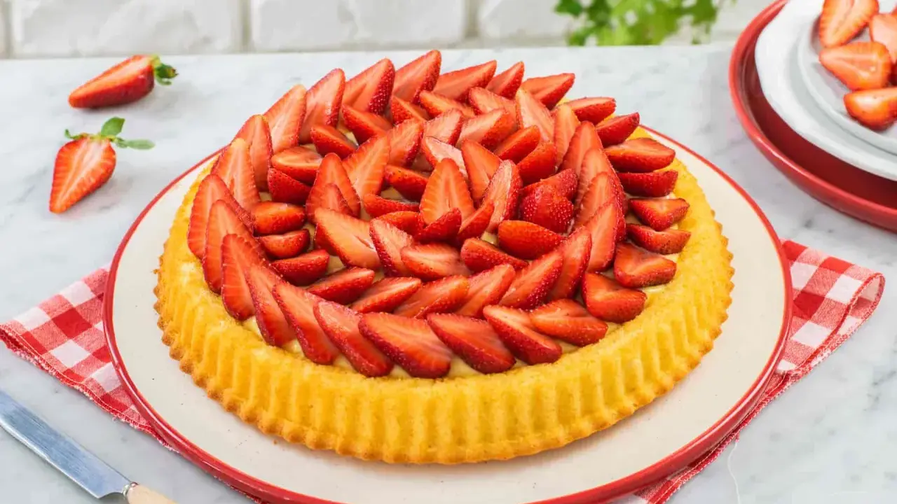 Una deliziosa crostata morbida alle fragole, con la sua base dorata e un abbondante strato di fragole fresche affettate.