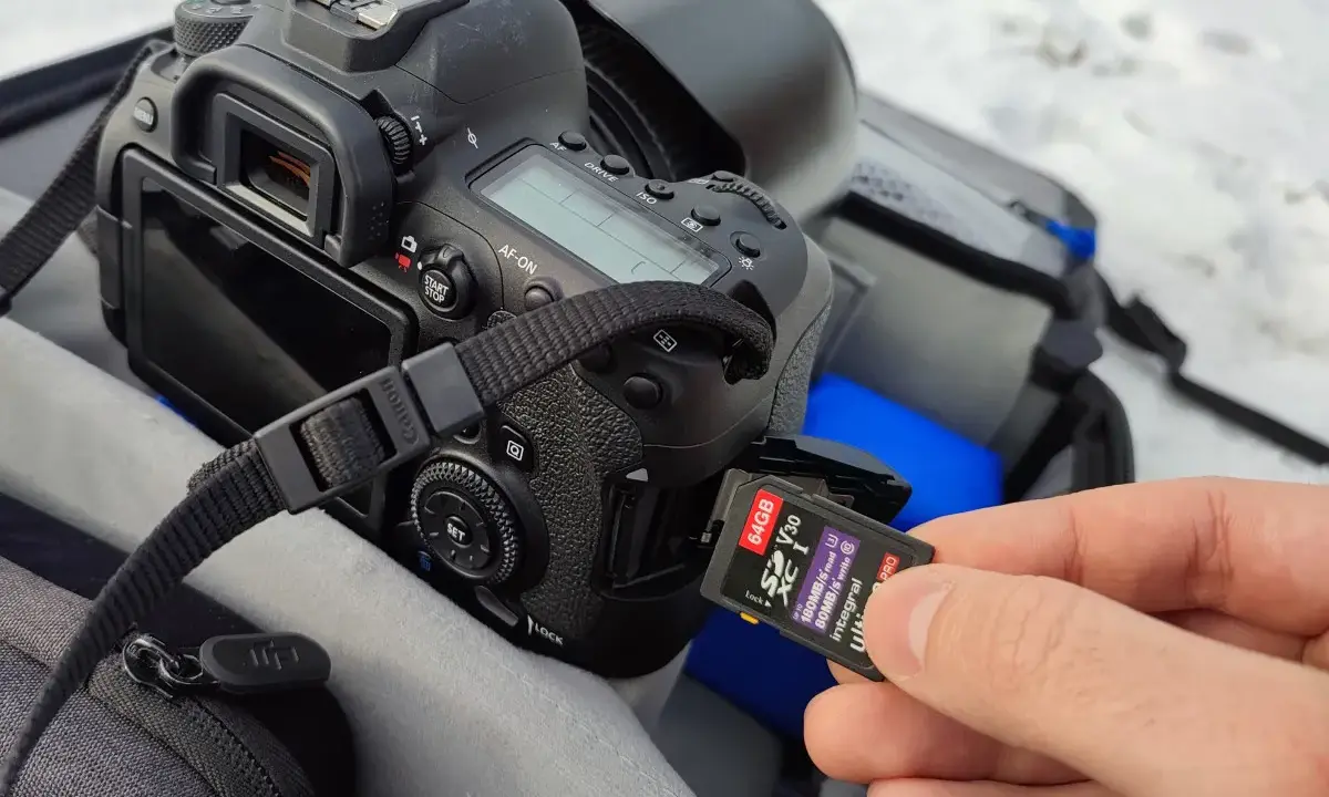 Dłoń wkłada kartę pamięci 64GB do aparatu. Ile to zdjęć? Z pewnością mnóstwo!