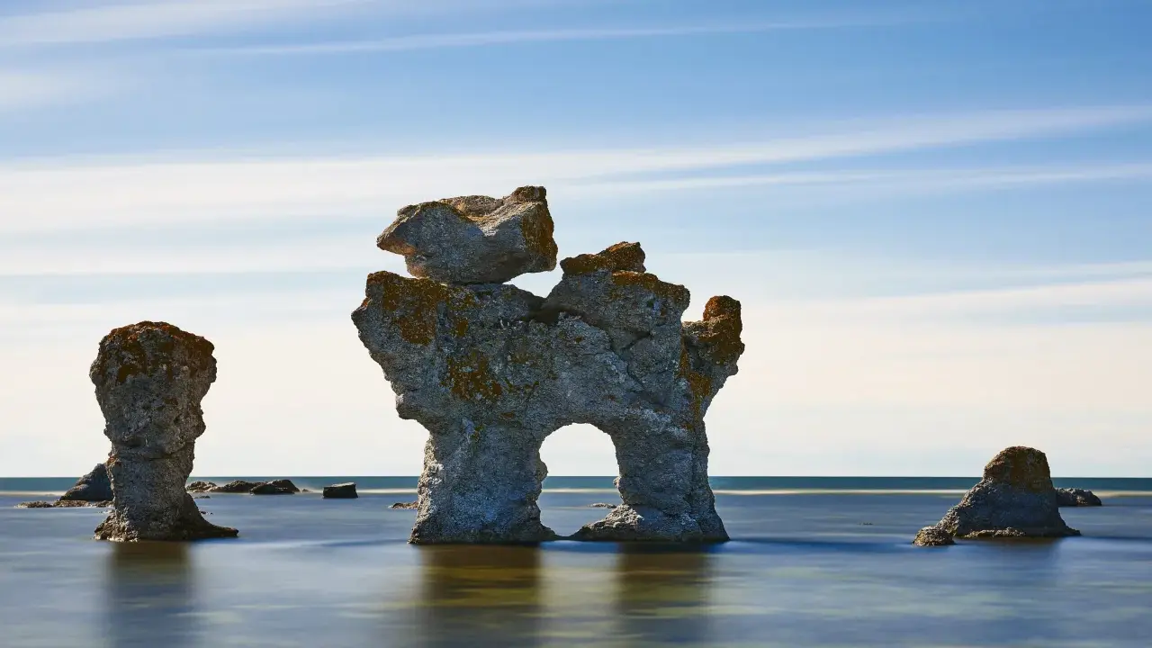 Raukar i havet vid Fårö, Gotland. En fantastisk vy att se på Gotland, med stenformationer som reser sig ur det blå vattnet under en molnig himmel.