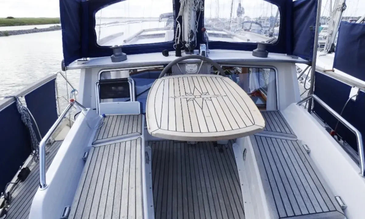 Cockpit d'un Nauticat 33 avec table en teck ornée d'une rose des vents. Détails techniques visibles.