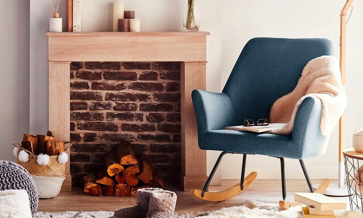 Un fauteuil bleu confortable invite à la détente près d'une cheminée en briques, créant un coin cheminée cocooning parfait pour lire.