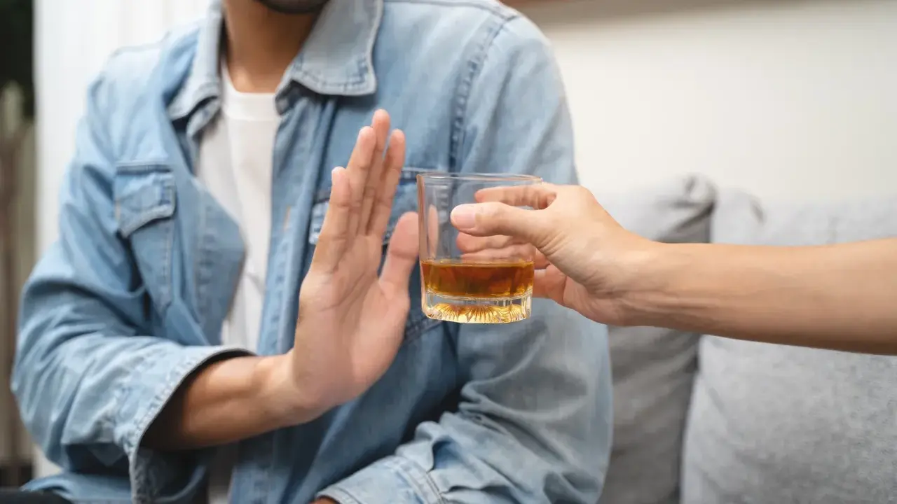 Mężczyzna odmawia alkoholu, symbolizując dobrowolne leczenie odwykowe i nowy początek.