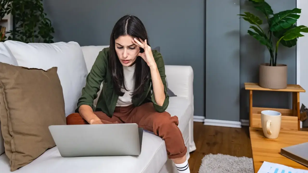 Introwertyczka skupiona na pracy przy laptopie na kanapie. Idealna praca dla introwertyka, gdzie można pracować w spokoju.