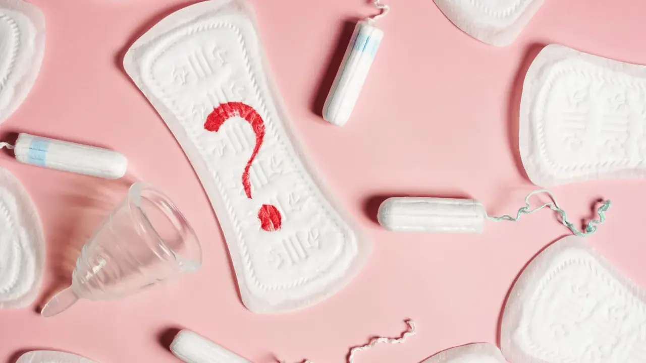 Pytajnik z krwi na podpaskach, obok tampony i kubeczek menstruacyjny. Czy to plamienie przed okresem?