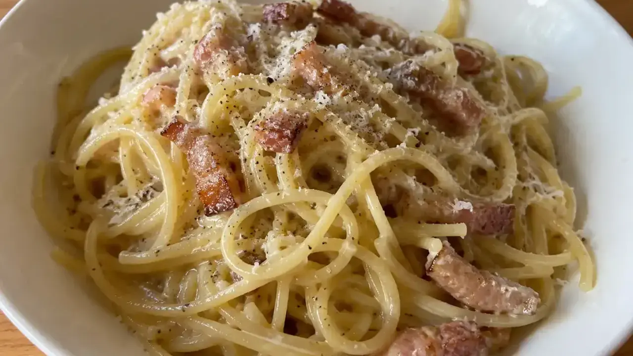 En krämig portion pasta carbonara med knapriga bitar av fläsk och rikligt med svartpeppar.
