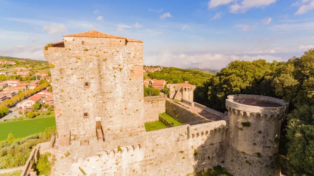 Il castello di Sarteano domina il borgo con le sue mura antiche e torri imponenti, circondato dal verde della campagna toscana.