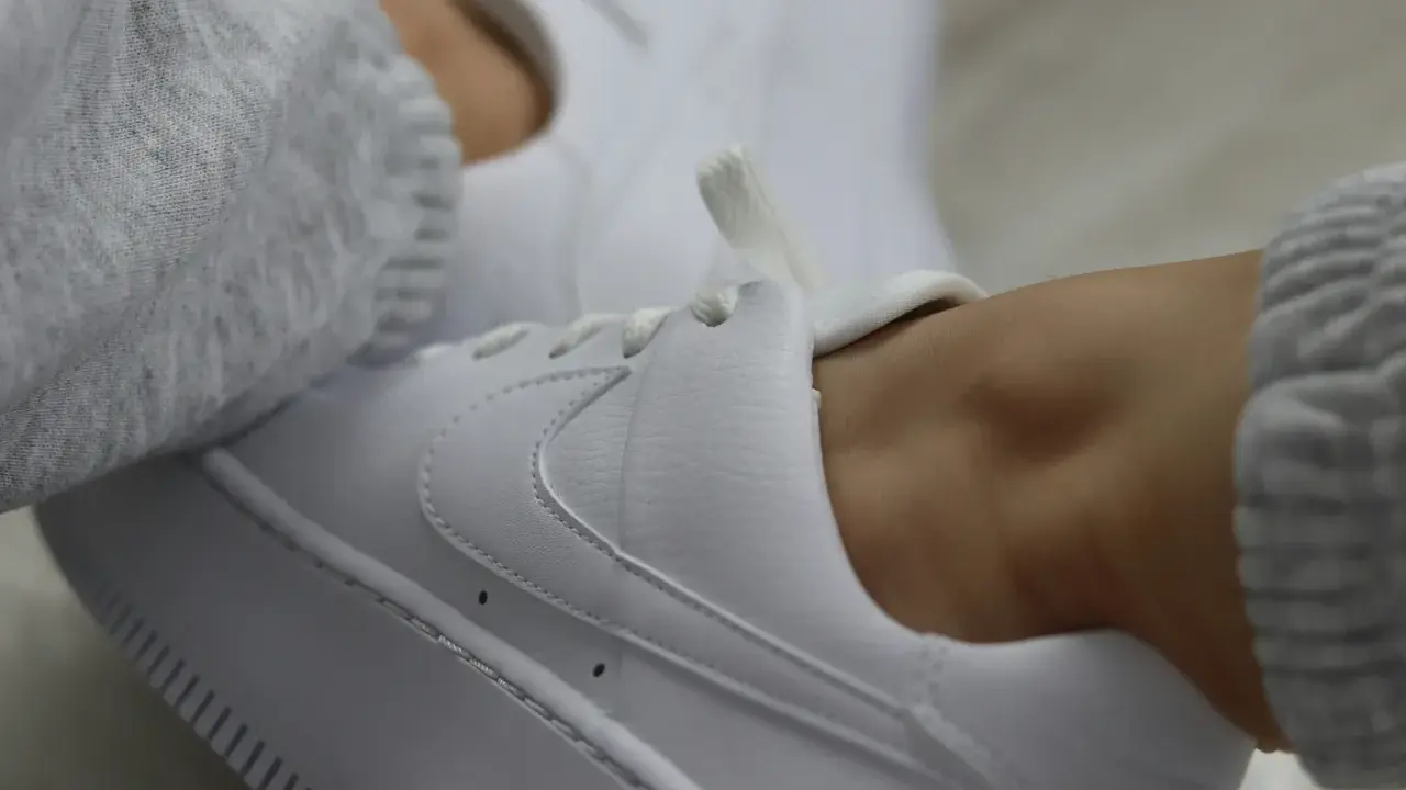 Białe sneakersy z szarym swetrem. Dowiedz się, jak zabezpieczyć białe buty, by długo wyglądały jak nowe.