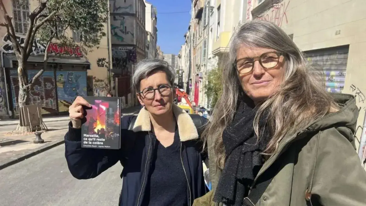 Deux femmes, l'une tenant un livre, dans une rue de Marseille. Le visage de madone de l'une d'elles est encadré par des lunettes.