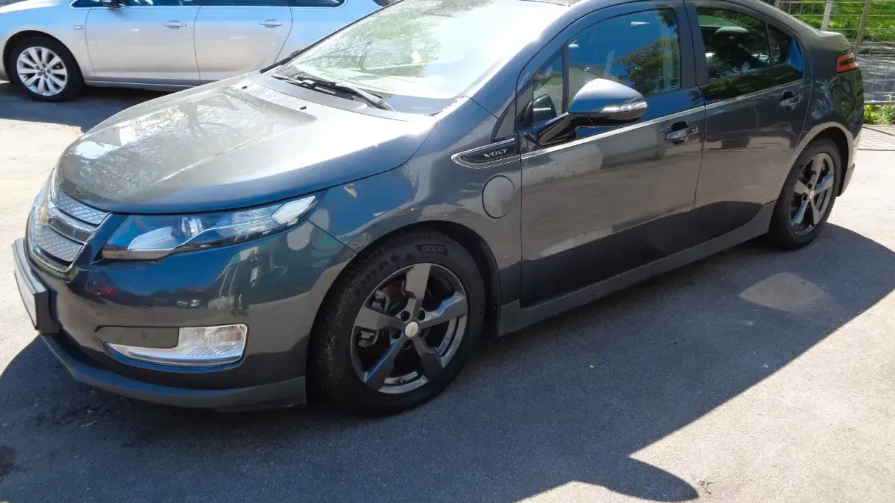 Ciemnoszary Chevrolet Volt stoi na parkingu. Obok niego widać srebrne kombi.