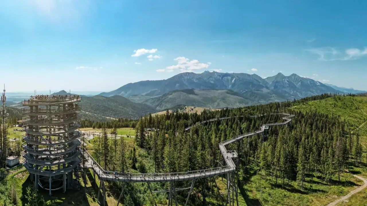 Spacer w chmurach Zakopane: drewniana wieża widokowa i ścieżka w koronach drzew pośród zielonych lasów i gór.