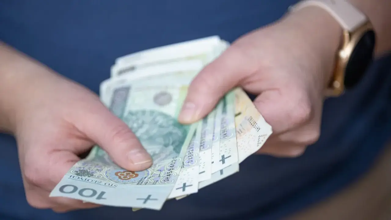Dłonie trzymające polskie banknoty 100 zł. Czy to nagroda, czy może podatek od nagrody?