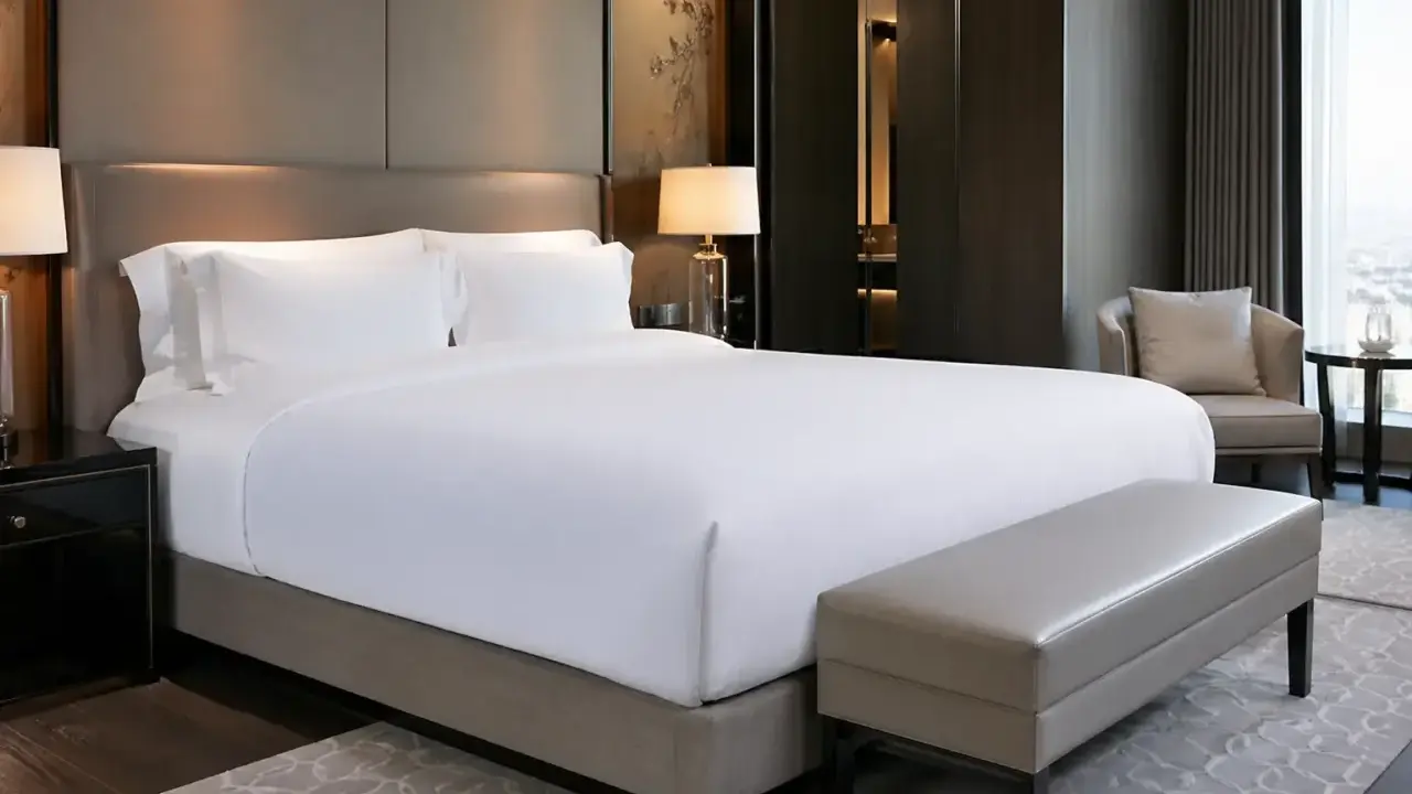 Cama de hotel con sábanas blancas impecables. ¿De qué marca son los colchones de los hoteles? Este lujoso dormitorio invita al descanso.