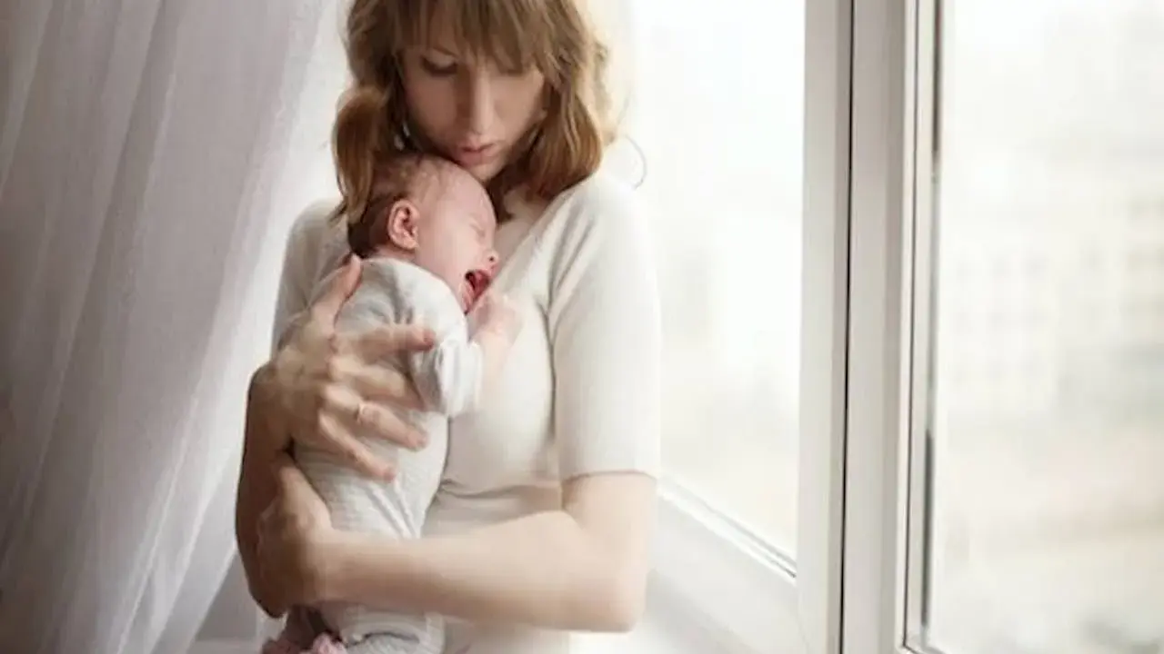 Zmęczona mama tuli płaczące dziecko, które właśnie robi kupę w nocy.