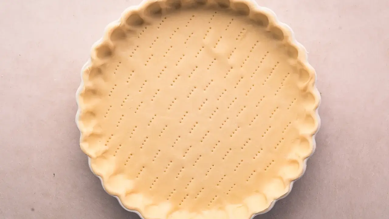 Pâte brisée salée prête à être garnie. Les petits trous préparent la base pour une cuisson parfaite.