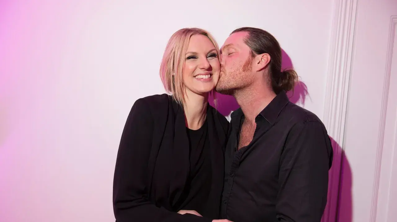 Sanna Nielsen ler när en man med hästsvans ger henne en puss på kinden.