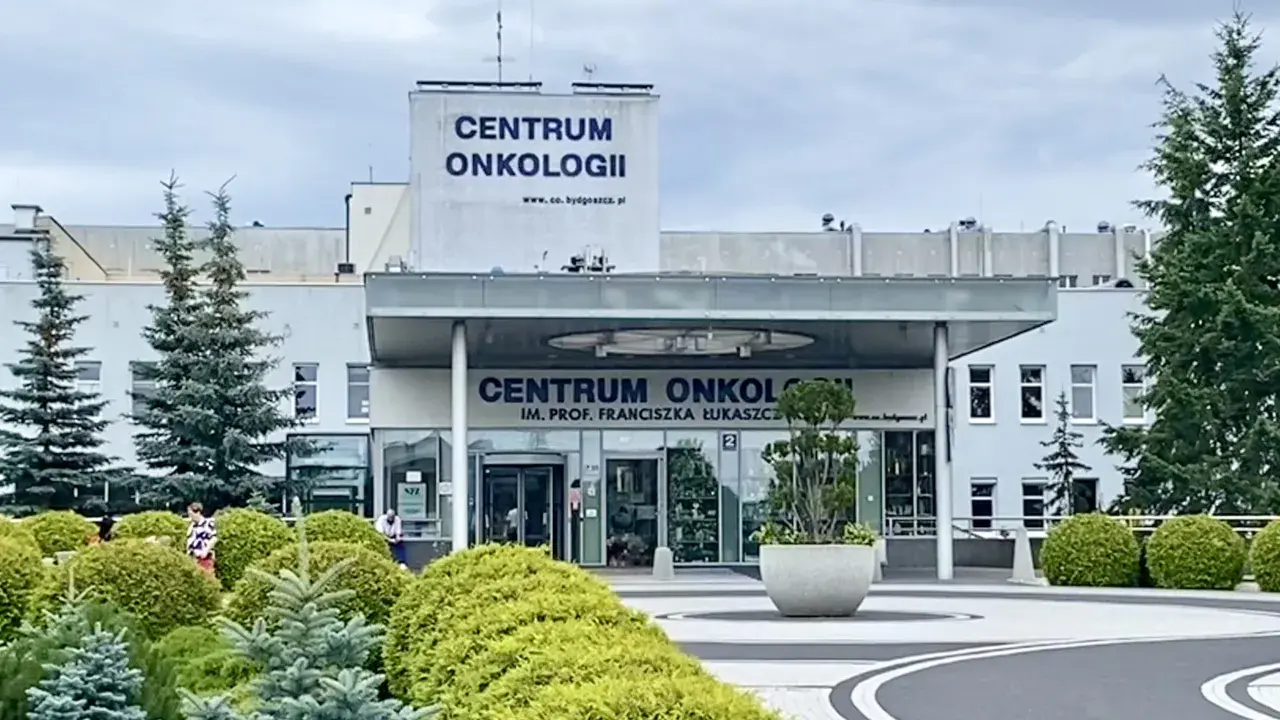 Budynek Centrum Onkologii w Bydgoszczy z zielenią przed wejściem.