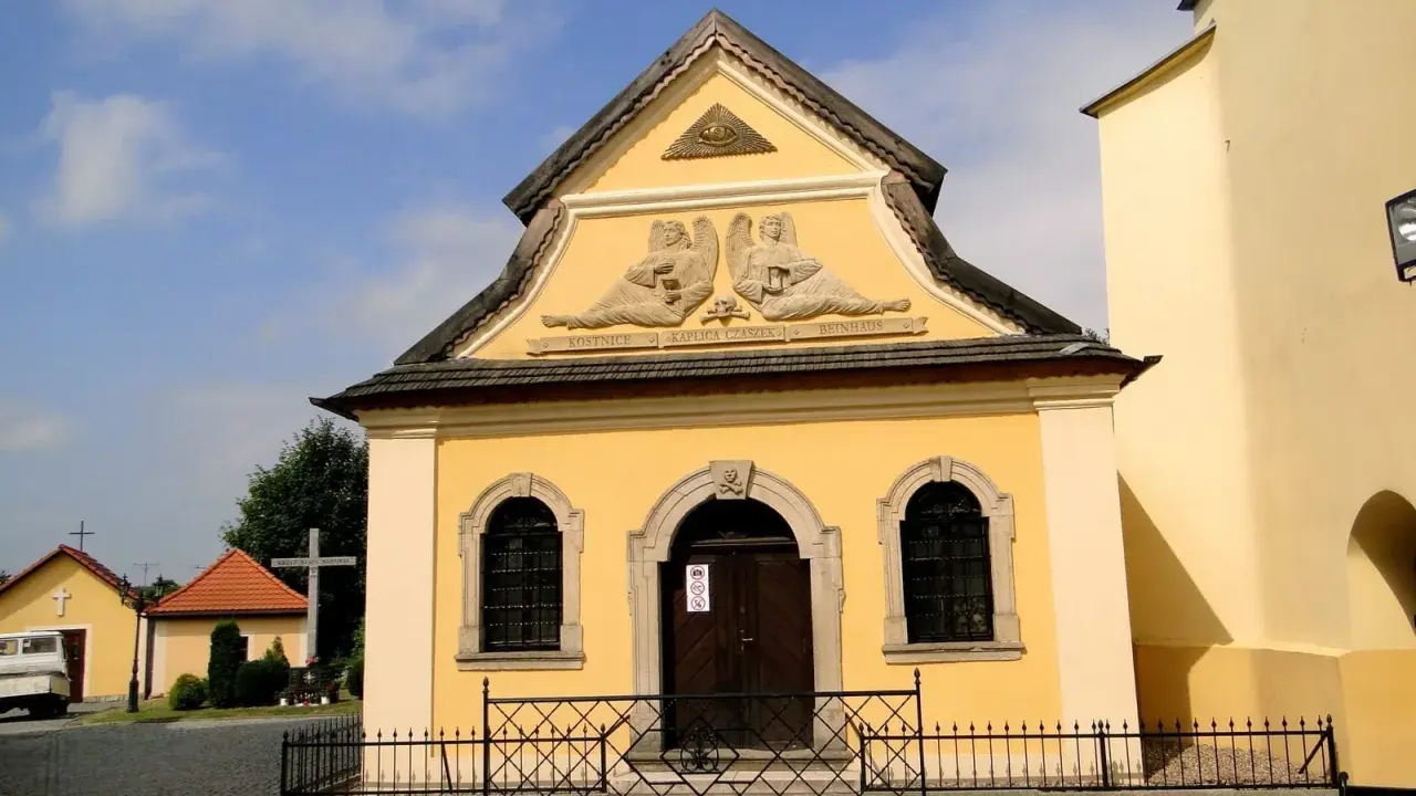 Żółta kaplica czaszek w Czermnej z aniołami i napisem "Kaplica Czaszek".
