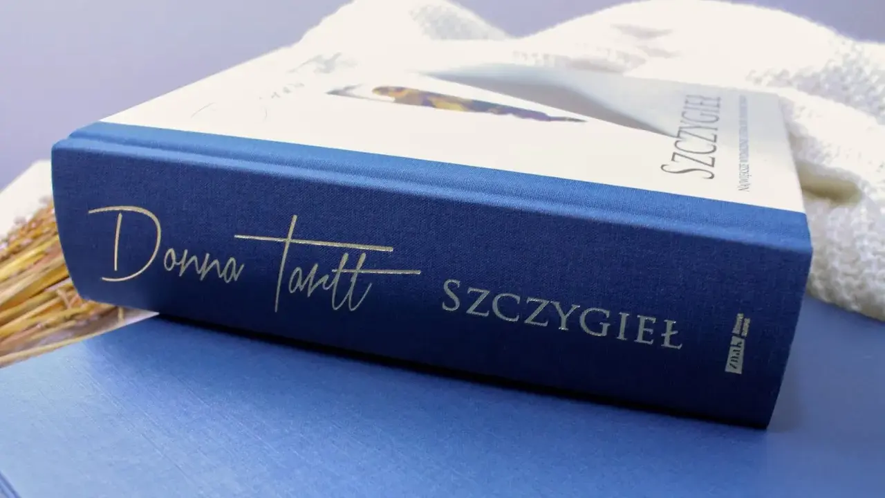 Granatowa okładka książki "Szczygieł" Donny Tartt z wytłoczonym złotym napisem.