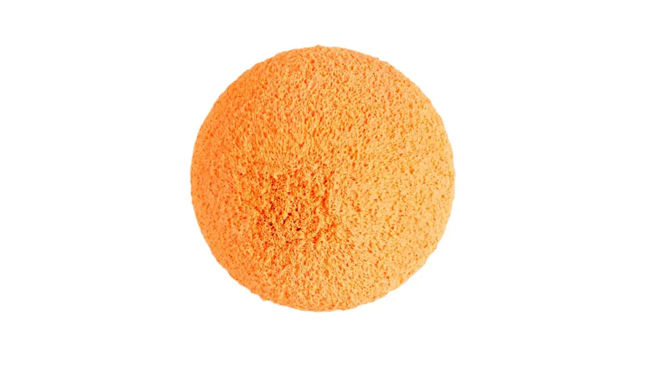 Une balle de nettoyage orange, texturée et spongieuse, prête à faire briller votre maison.