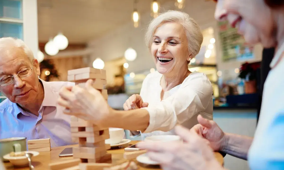 Anziani sorridono giocando a Jenga, un'attività stimolante per anziani con demenza.