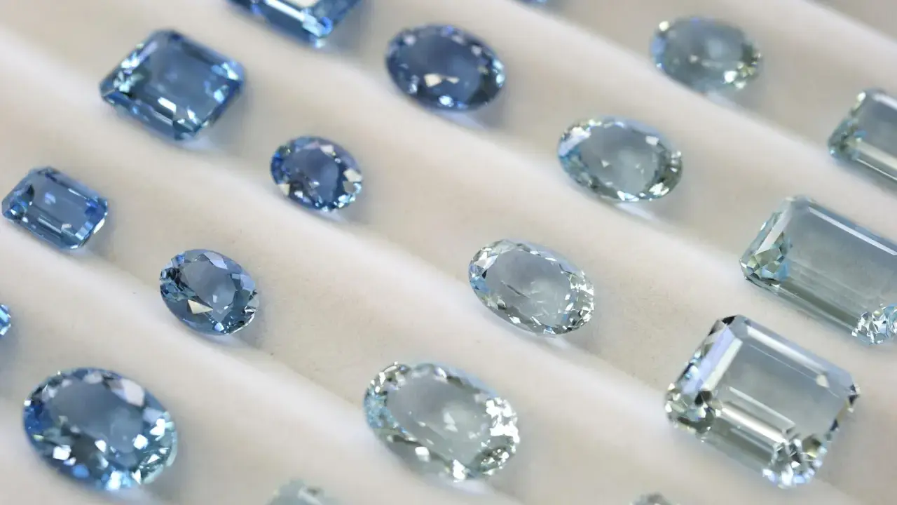 Collezione di acquamarine con taglio smeraldo e altre forme, che brillano su un morbido sfondo bianco.