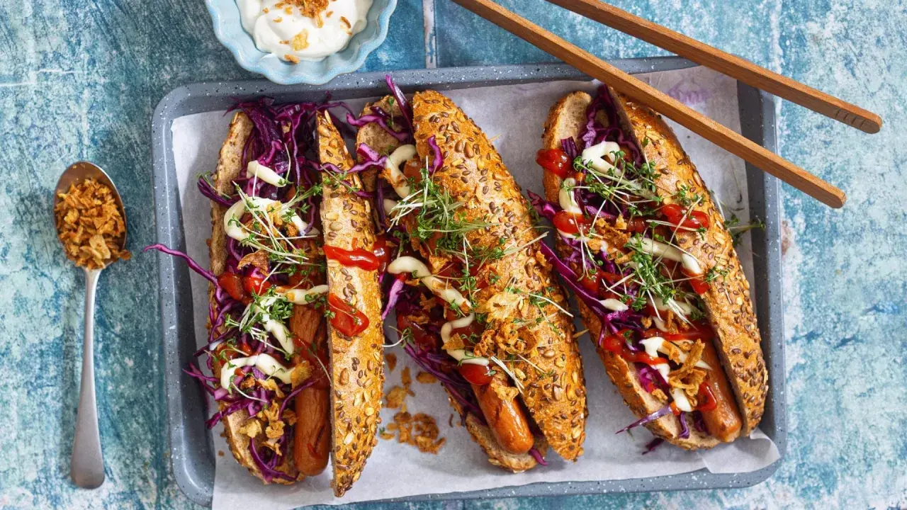 Drei leckere Hotdogs mit Rotkohl, Kresse und Röstzwiebeln – perfekt für vegetarisches Grillen!