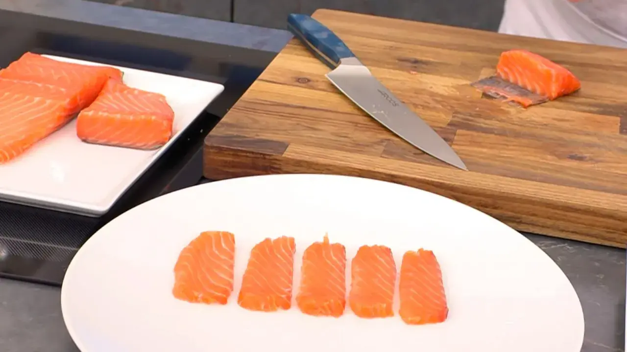 Filetes de salmón marinado listos para servir. Un cuchillo y una tabla de cortar de madera sugieren preparación.