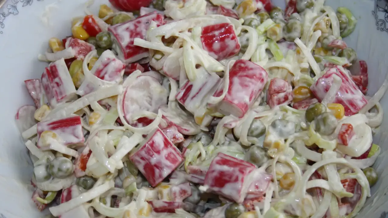 Pyszna sałatka z paluszkami surimi, groszkiem, kukurydzą i porem, polana kremowym sosem.