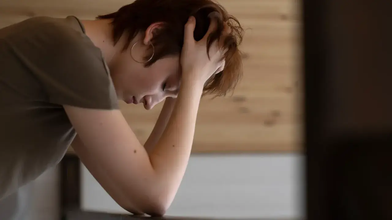 En person med händerna i håret, ser nedåt. Kanske en bild som visar hur man kan tänka kring hur minskar man stress.