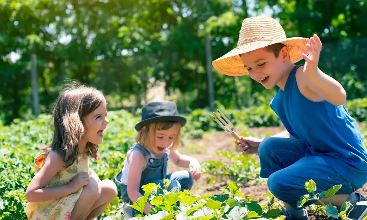 Bambini felici in un orto, un'esperienza divertente nelle fattorie per bambini nelle Marche.